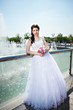 Happy bride about fountain with bouquet