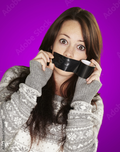 Photo: portrait of scared girl being silenced by herself over purple ba portrait of scared girl being silenced by herself over purple ba