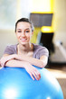 Attractive young woman leaning on an exercise ball at the gym