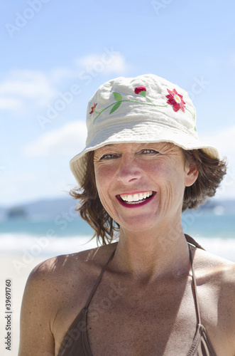 Photo: Happy laughing woman on beach wearing hat Happy laughing woman on beach wearing hat