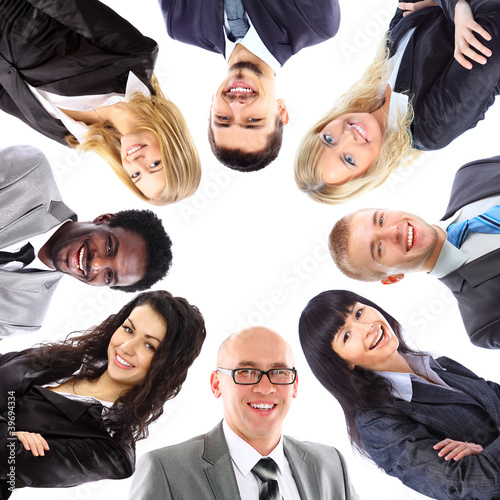 Photo: Group of business people standing in huddle, smiling Group of business people standing in huddle, smiling