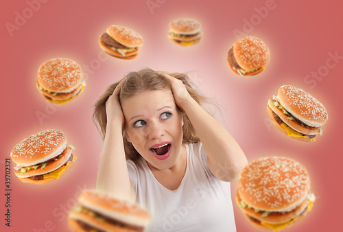 Photo: diet concept. young woman is under stress, burgers are flying ar diet concept. young woman is under stress, burgers are flying ar