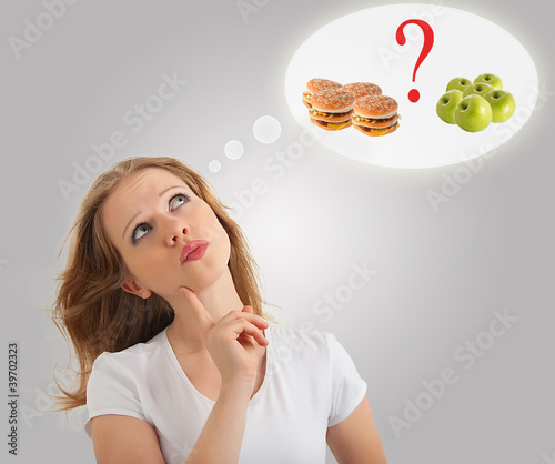 Photo: attractive young woman makes a choice between healthy and unhea attractive young woman makes a choice between healthy and unhea