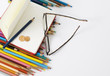 Color pencils, notebook, eye glasses and few euro coins.