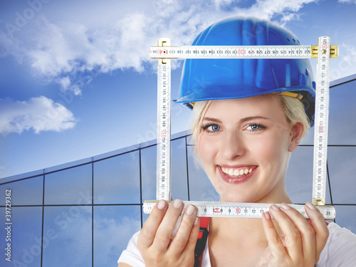 Foto: Young female builder takes measurements for housebuilding Young female builder takes measurements for housebuilding