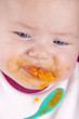 baby girl eating her first mashed carrot