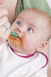 baby girl eating her first mashed carrot