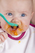 baby girl eating her first mashed carrot