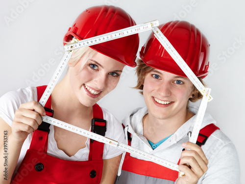 Photo: Pretty young couple in overalls with yardstick Pretty young couple in overalls with yardstick