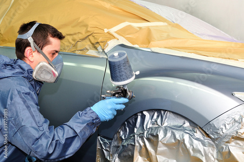 Photo: Worker painting a car. Worker painting a car.