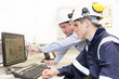 Senior and junior engineers discussing work together in office