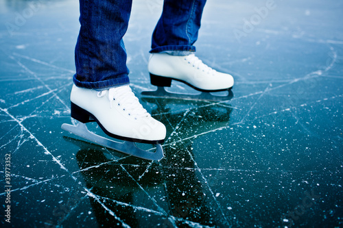 Photo: Young woman ice skating outdoors on a pond on a freezing winter Young woman ice skating outdoors on a pond on a freezing winter