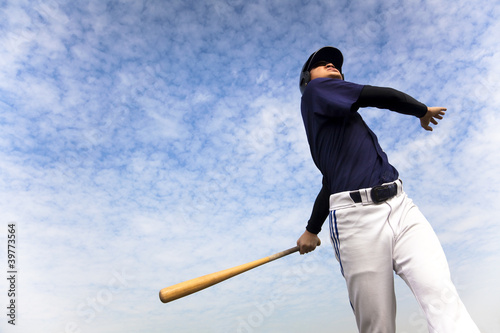 Photo: baseball player taking a swing with cloud background baseball player taking a swing with cloud background