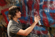 Teenager spray painting a rock