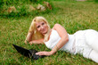 Young beautiful woman working with laptop in the green grass
