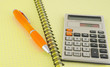Old calculator and pen on the yellow writing-book Old calculator and pen on the yellow writing-book