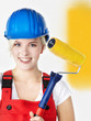 Young woman in overall is painting her wall yellow