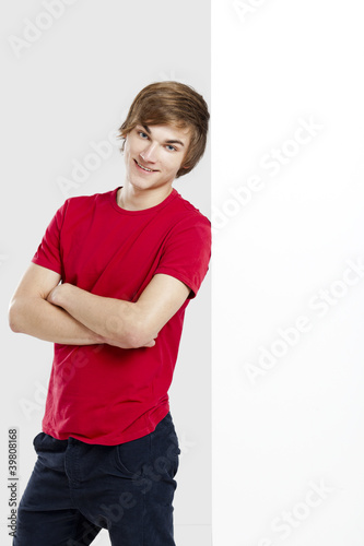 Photo: Portrait of a happy young man next to a blank white card Portrait of a happy young man next to a blank white card