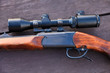 Sniper rifle with optical sight on wooden table.
