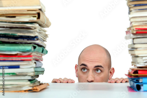 Photo: Man staring nervously at piles of folders Man staring nervously at piles of folders