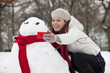 Photo: A young woman photographing a snowman A young woman photographing a snowman