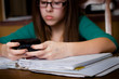 Girl Distracted by Texting on Cell Phone while Doing Homework