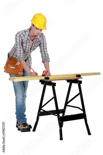 Photo: Woman measuring plank of wood Woman measuring plank of wood