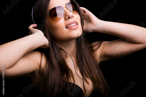Photo: Beautiful young woman listening to music with headphones on blac Beautiful young woman listening to music with headphones on blac