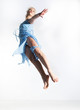 Motion. Young woman in blue dress jumping in studio