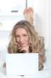 blonde woman doing computer on a couch