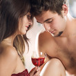 Young enamoured couple drinking red wine on the bed in bedroom Young enamoured couple drinking red wine on the bed in bedroom