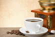 cup of coffee with beans and grinder