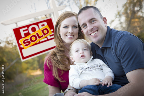 Photo: Happy Young Family in Front of Sold Real Estate Sign Happy Young Family in Front of Sold Real Estate Sign