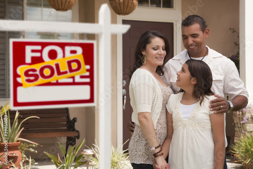 Photo: Hispanic Family in Front of Home with Sold Real Estate Sign Hispanic Family in Front of Home with Sold Real Estate Sign
