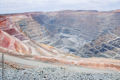 Photo: Big mine pit with little dump trucks and reddish soil Big mine pit with little dump trucks and reddish soil