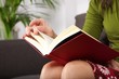 woman detail sitting on a brown sofa reading a book