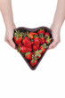 hands showing a heart shaped bucket  with fresh strawberries