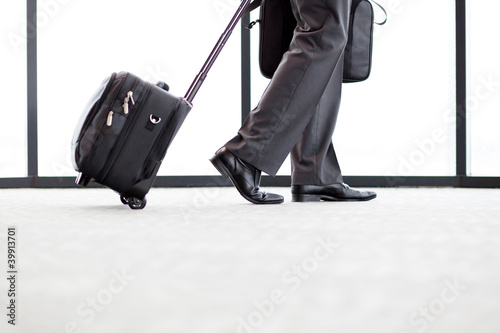 Photo: businessman walking in airport with his luggage businessman walking in airport with his luggage