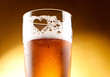Glass of beer with the heart represented with froth close up ove