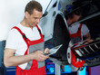 Motor mechanic is working in a garage with touchpad