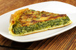 Photo: Slice of spinach tart with parmesan - wooden background Slice of spinach tart with parmesan - wooden background