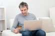 Senior man shopping at home using laptop