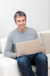 Senior man sitting in sofa and using laptop