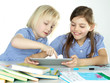 Photo: Two cute girlfriends learning with books and touchpad Two cute girlfriends learning with books and touchpad