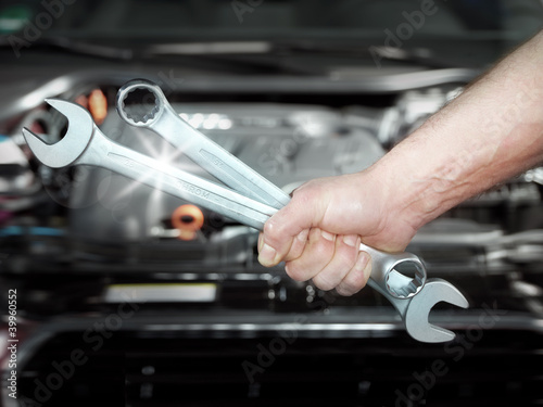 Photo: Close up of a hand with tools in front of an engine bay Close up of a hand with tools in front of an engine bay