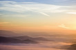 colorful summer morning with golden light and fog between hills
