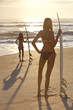 Women Surfers In Bikinis With Surfboards At Sunset Beach