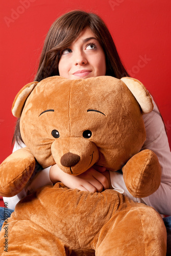Photo: Young woman embracing teddy bear looking up sitting close-up Young woman embracing teddy bear looking up sitting close-up