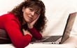 Foto: Woman lying on the couch with your laptop Woman lying on the couch with your laptop