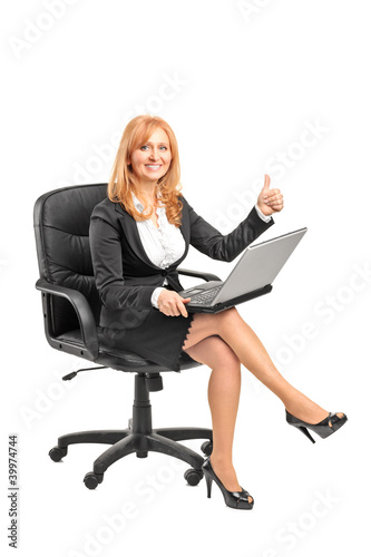 Foto: Businesswoman working on a laptop and giving thumb up Businesswoman working on a laptop and giving thumb up